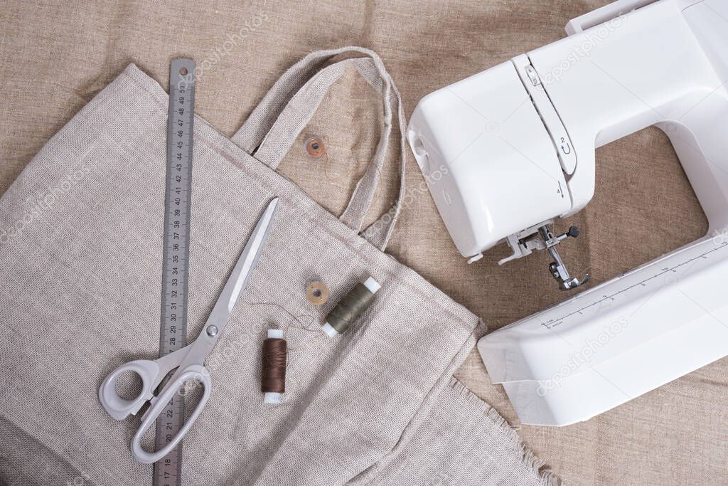 sewing machine, homemade eco shopper, scissors and thread on linen fabric, zero waste lifestyle