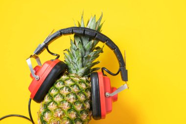 Sarı arka planda kırmızı retro kulaklıklı ananas, müzik aşığı konsepti boşluğu kopyala