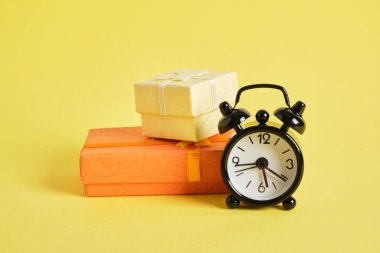 Siyah retro alarm saati ve hediye kutusu sarı arka plan fotokopi alanı. Kutlama zamanı.