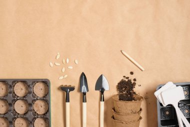 Kraft kağıdındaki bahçe araçları. Üst görünüm, küçük spatüller tabaklar ve turba kapları. Tohum ekmek için her şey.
