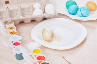 Paskalya için yumurta, yumurta kutusu, paskalya yumurtası, tabak, fırça ve ahşap masa boyası boyama işlemi