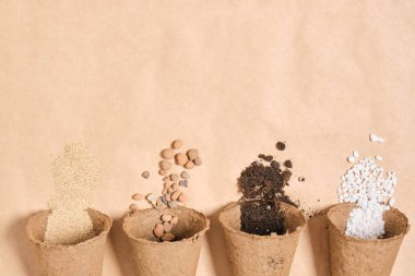 Bitkiler için verimli toprak, drenaj için taşlar, perlit, tohum için toprak, bahçe için gübre hazırlamak için farklı malzemelere sahip birkaç turba tenceresi.