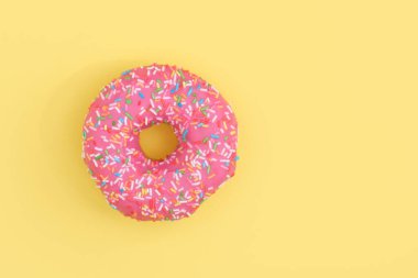 Pembe kremalı çörek ve sarı arka plan fotokopi alanı üzerine pasta serpiştirilmiş.