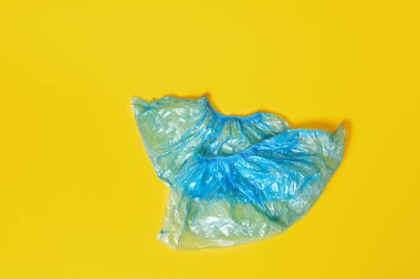 Sarı arkaplan arkaplanındaki mavi plastik ayakkabı kapakları kopya alanı