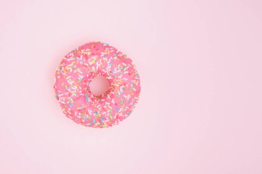 Pembe kremalı çörek ve pembe arka plan fotokopi alanına serpiştirilmiş pasta.