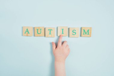 Ahşap karelerde otizm ve mavi arka planda küçük bir çocuğun el yazısı.