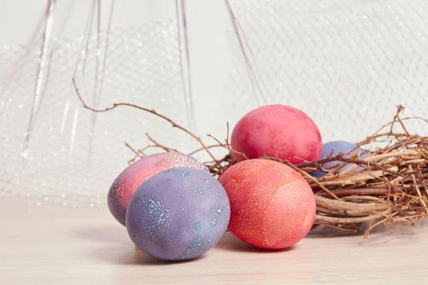 boyalı Paskalya yumurtaları ve ağaç bir masanın dallarından yapılmış dekoratif bir yuva.