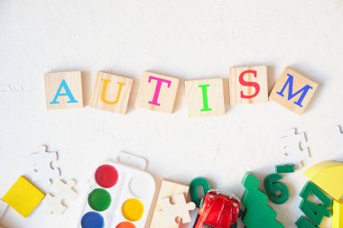 suluboya resimler ve çocuklar hafif arka planda eğitici oyuncaklar, ahşap karelerde yazılı otizm