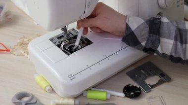 Kadınlar dikiş makinesinin mekanizmasını özel bir fırçayla içeriden tozdan fırçalar.