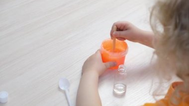 Küçük kız yanlarına pembe balçık serpiştiriyor. Çocuk elleri sümük oyuncağı oynuyor. Balçık yapıyorum.