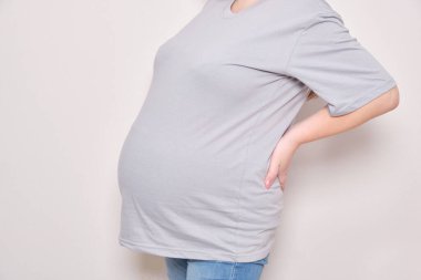 Sırtı ağrıyan hamile kadın gövdesi fotokopi alanı tutuyor.