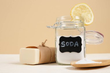 Temizlik için çevre dostu temizlik seti, soda ve limon, sıfır atık yaşam tarzı konsepti. Cam kavanozda kabartma tozu, sabun, luffa ve bej arka planda dilimlenmiş limon.