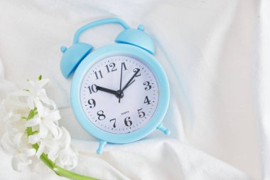mavi alarm saati ve yatakta çiçek, bahar sabahı konsepti kopyalama alanı