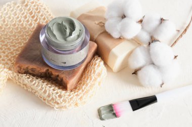 sabun, bez, yüz ve vücut için kozmetik mavi kil, hafif arkaplanda kil ve pamuk çiçekleri uygulamak için fırça