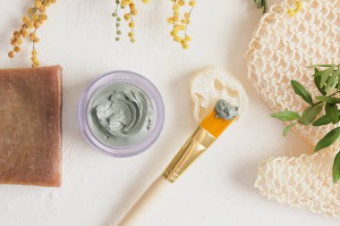 Kozmetik mavi kil, bez, fırça, lif, kokao sabunu ve çiçekler açık arkaplan spa konseptinde.