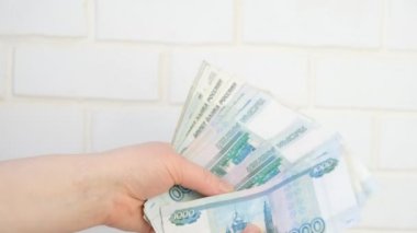 Kadın eli para sayıyor, tuğla duvarın arkasında 1000 ruble banknotlar, 4k ruble video içinde bir sürü para.