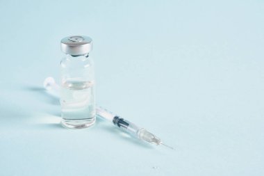 Mavi arkaplan üzerinde enjeksiyon için ilaç içeren insülin şırıngası ve şişe fotokopi alanı, aşı kavramı