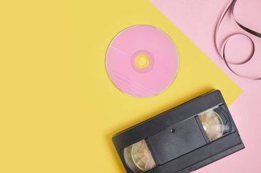 Pembe ve sarı arkaplanda cd disk ve video kaset, Pembe etiketli CD CD CD kaset üst görünümü