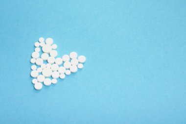 Mavi arkaplanda beyaz haplardan oluşan kalp şeklindeki fotokopi alanı üst görünümü