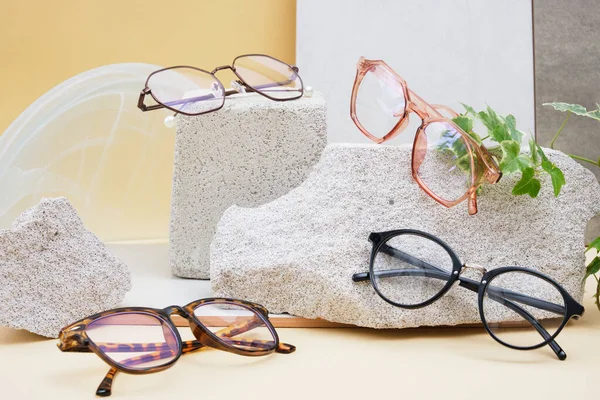 multiple eye glasses on concrete podiums on a beige background, trend composition, stylish eye glasses on a beige background with plants and tiles