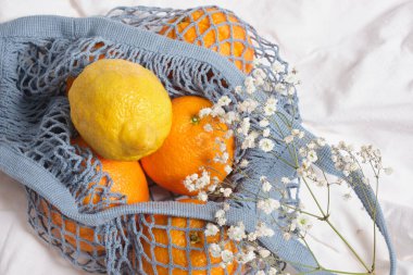 Buruşmuş beyaz kumaş kopyalama alanı üzerinde portakal ve limon dolu ağ eko torbası