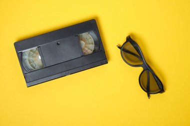 3 boyutlu filmler izlemek için gözlük ve pembe ve sarı arka planda video kaset, klasik video kaset kopyalama alanı