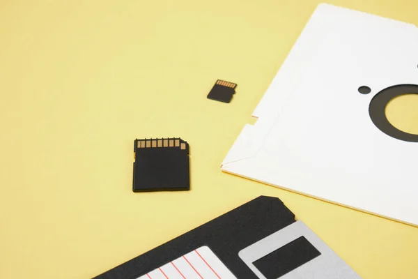 Verschillende soorten schijven voor het opslaan van informatie op een gele achtergrond, moderne flash kaarten en retro diskettes — Stockfoto