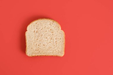Kırmızı arka planda izole edilmiş bir dilim ekmek. Boşluk üst görünümünü kopyala