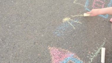 Kız yazın sokağın ortasında tebeşirle güneşi çiziyor.