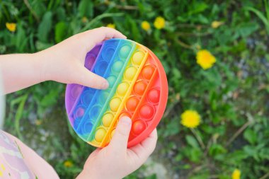 Çocuk çok renkli oyuncaklarla oynuyor, anti-stresi sokağa at, arka plandaki çimenleri kopyala.