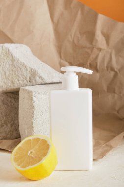 Sabun iyoi kremi, limon ve beton podyumlar için beyaz plastik şişe, kahverengi arka plan, buruşuk kağıt, sahte kozmetik
