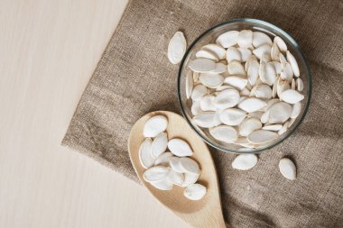 Beyaz kasede kabak çekirdeği ve masada keten kaşık fotokopi alanı.
