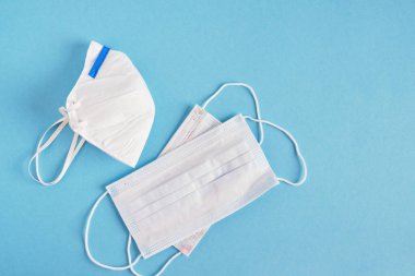 Mavi arka planda antiviral tıbbi yüz maskesi olan beyaz KN95 veya N95 maskesi. Cerrahi koruyucu maske üst görünüm kopyalama alanı