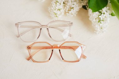 Bir kaç farklı gözlük ve bej arkaplan, gözlük ve çiçek desenli beyaz leylak dalı yer kopyalayabilir.