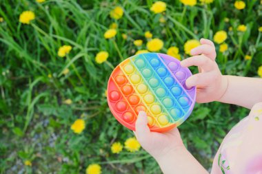 Çocuk çok renkli oyuncaklarla oynuyor, anti-stresi sokağa at, arka plandaki çimenleri kopyala.