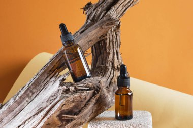 Kahverengi cam şişeler beton bir podyumda tahta bir tahta zemin üzerinde pipetle, kahverengi arka plan fotokopi alanı doğal kozmetik konsepti