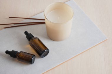 aroma çubukları, pipetli kahverengi cam şişe ve seramik fayans üzerindeki aroma mumu, serum ya da vücut bakımı için doğal yağ kozmetiği.