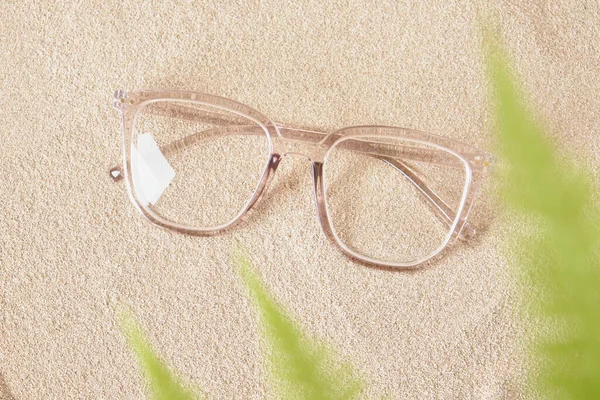 Stylové Oční Brýle Průhledném Plastovém Rámu Písku Kapradinové Listy Rozmazaném — Stock fotografie
