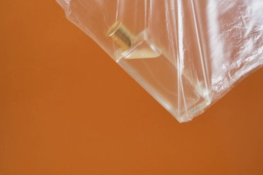Kahverengi arka planda plastik bir poşette bir parfüm şişesi. Orijinal fikir. Uzay çevre dostu fotokopi çek ve plastik kavram kullanma.
