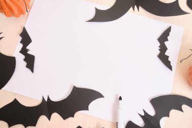Ev yapımı cadılar bayramı dekoru ve masanın üzerinde bir sayfa kağıt, balkabağı ve kağıt yarasalar çerçeve, uzay üst görünümünü kopyala