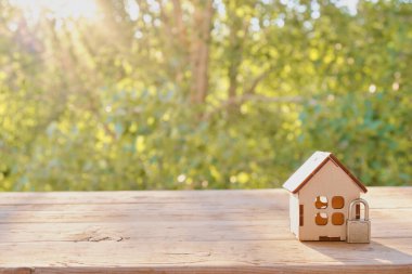 Ev güvenliği kavramı: ahşap model ev ve ahşap yüzeye kilitlenmek. Doğa yeşili bokeh arka plan. ev güvenliği