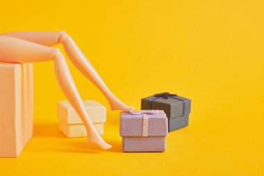 Bebek bacakları ve sarı arka planda hediye kutuları, bir sürü oyuncak bacak, ayakkabı mağazası ve satış sezonu fotokopi alanı.