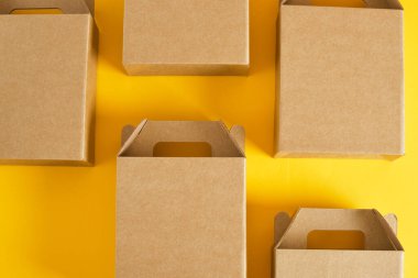 Sarı arka planda birkaç karton kutu, hediye ya da ürün teslimatı için logo olmadan kutular, tasarımınız için boş paket