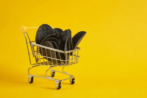Black Potato Chips Mini Shopping Cart Yellow Background Copy Space — Stock Photo, Image