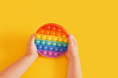 Renkli oyuncaklar, el becerilerinin gelişimi için sarı bir arka planda, duygusal bir oyuncağa takılır.