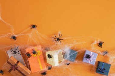 Bir sürü siyah plastik örümcek ve turuncu arka planda örümcek ağında hediye kutuları. Kopya alanı, mutlu Cadılar Bayramı, Cadılar Bayramı hediyeleri.
