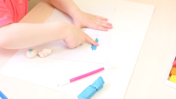 Девушка делает скульптуры из пластилина, ребенок рисует из пластилина на картонке — стоковое видео