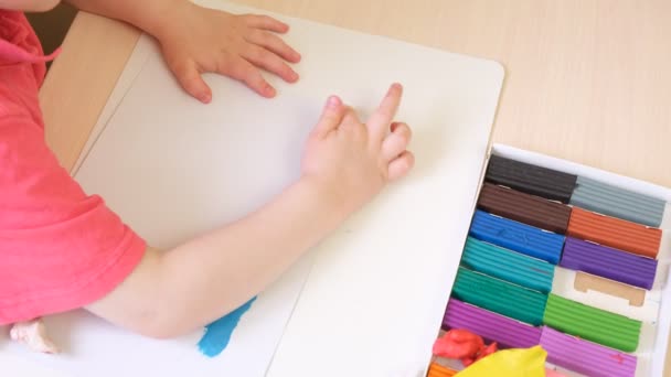 Девушка делает скульптуры из пластилина, ребенок рисует из пластилина на картонке — стоковое видео