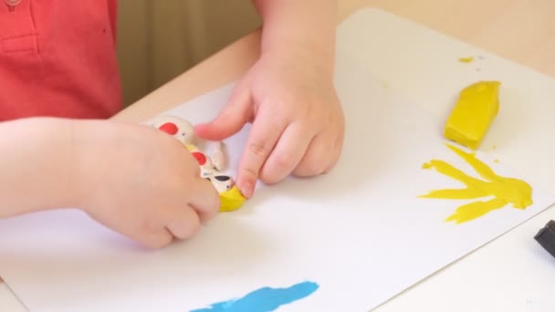 Une fille sculpte à partir de plasticine, un enfant fait un dessin à partir de plasticine sur carton — Video