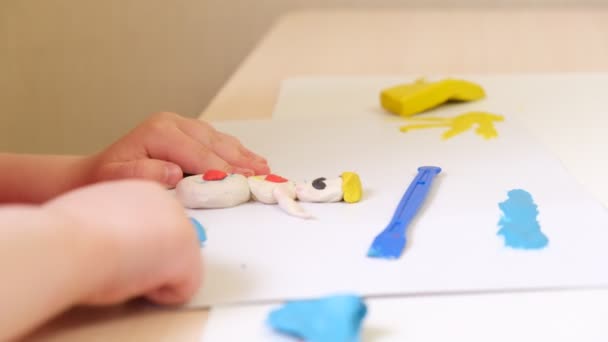 Дівчина скульптури з пластиліну, дитина робить малюнок з пластиліну на картоні — стокове відео